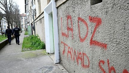 Des policiers patrouillent pr&egrave;s d'un panneau DZ Mafia tagu&eacute; sur la fa&ccedil;ade d'un immeuble dans un quartier d'Avignon (Vaucluse), le 13 mars 2025. (GABRIEL BOUYS / AFP)